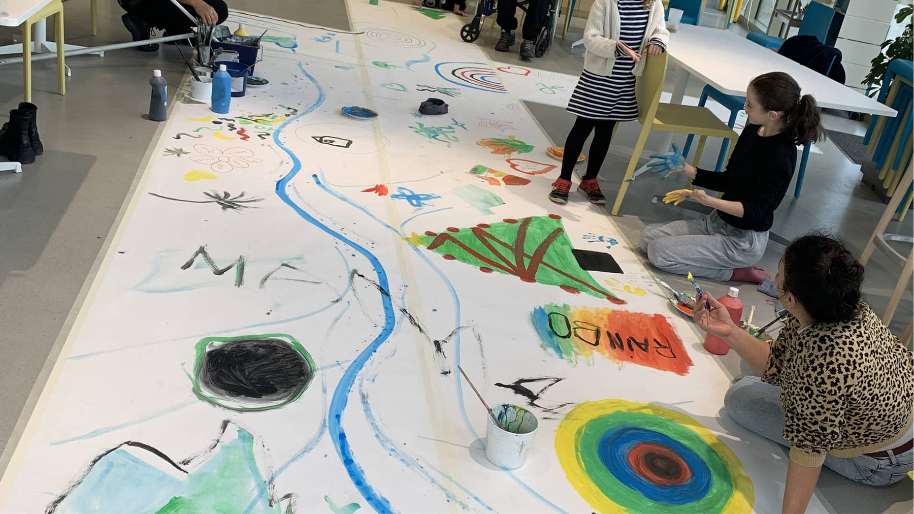 photo d'un atelier de peinture participative, de grand papiers peints par les personnes sont exposés au soldans une salle