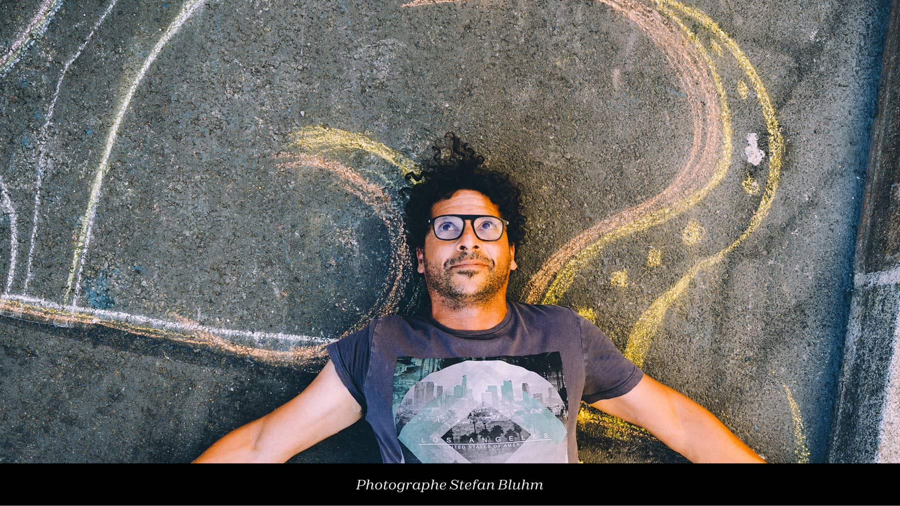 Photo de Diego Lis allongé sur le sol sur lequel une fresque a été dessiné